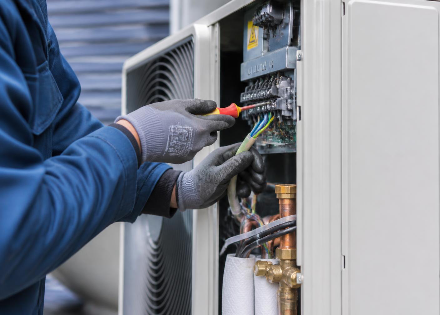 Installatore al lavoro sul collegamento elettrico di un'unità esterna di climatizzazione